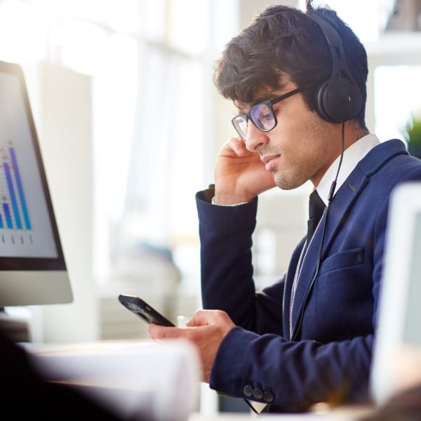 Businessman with smartphone and headphones listening to online program record for financiers